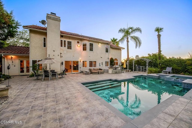 back of property with french doors, an outdoor living space, a patio, and a swimming pool with hot tub