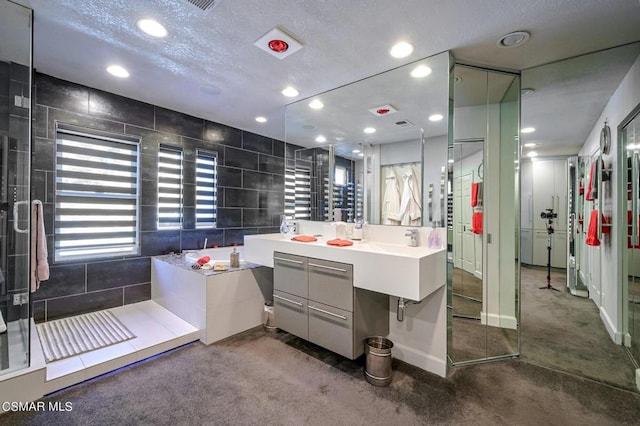 bathroom with vanity, a textured ceiling, separate shower and tub, and tile walls