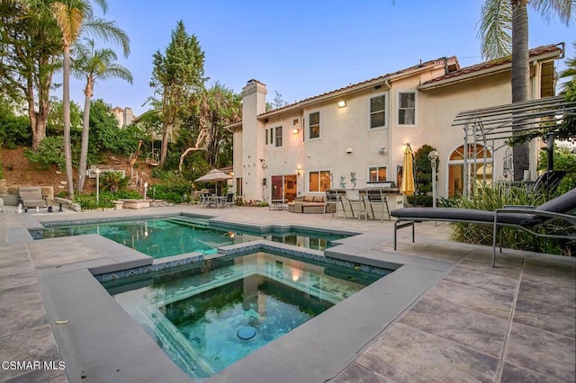 back of property featuring a patio area and a swimming pool with hot tub