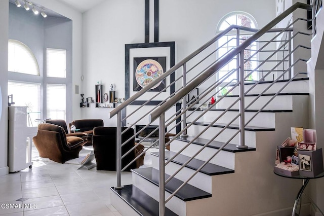 staircase with a towering ceiling and a healthy amount of sunlight