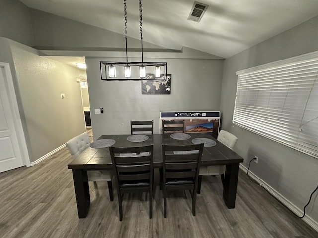 dining room with hardwood / wood-style flooring and vaulted ceiling