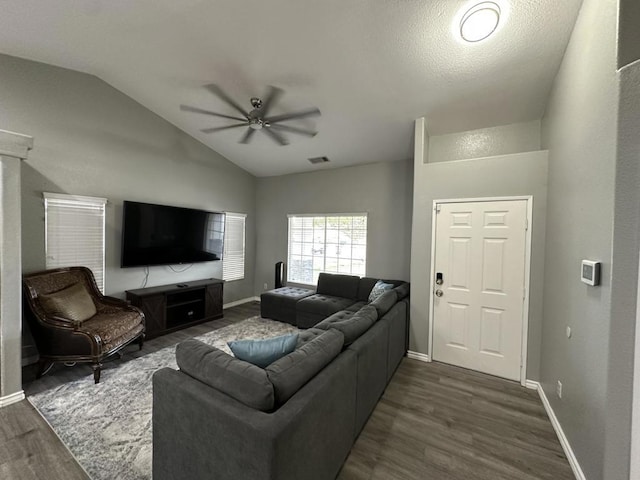 living room with ceiling fan, vaulted ceiling, dark wood-type flooring, and a textured ceiling