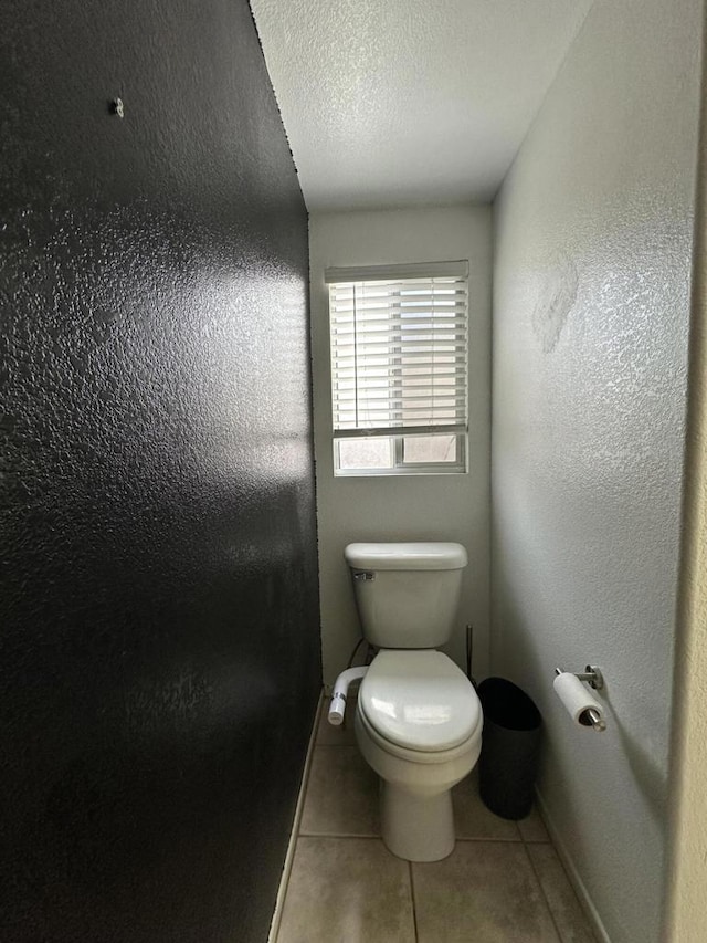 bathroom with a textured ceiling, tile patterned floors, and toilet