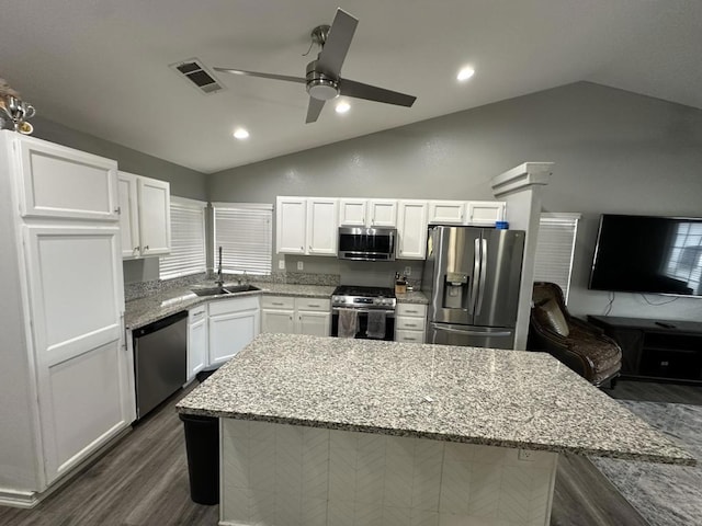 kitchen featuring lofted ceiling, white cabinets, appliances with stainless steel finishes, and light stone counters