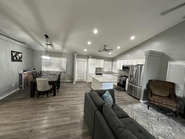 living room featuring ceiling fan, vaulted ceiling, sink, and hardwood / wood-style floors