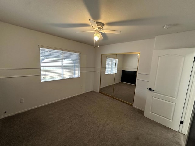 unfurnished bedroom with ceiling fan, dark carpet, and a closet