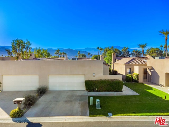 view of front facade featuring a mountain view, a front yard, and a garage