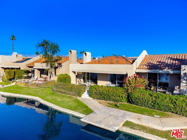 rear view of house featuring a water view and a yard