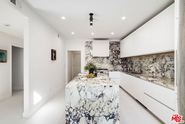 kitchen with backsplash, white cabinetry, and sink