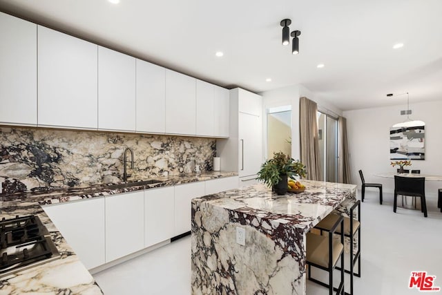 kitchen with white cabinetry, sink, tasteful backsplash, black gas cooktop, and light stone counters