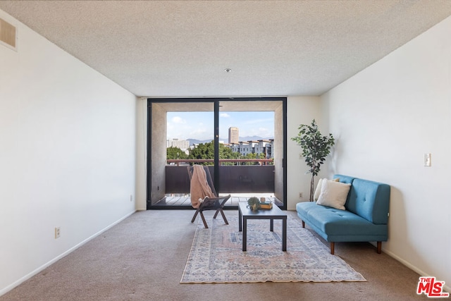 living area featuring a textured ceiling, carpet floors, and a wall of windows