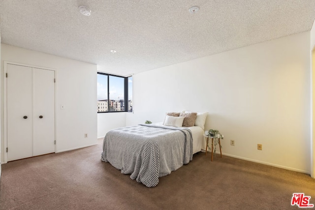 carpeted bedroom with a textured ceiling and a closet