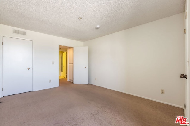 unfurnished bedroom with light carpet and a textured ceiling