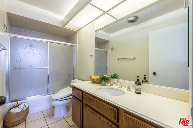 full bathroom featuring toilet, vanity, tile patterned floors, and enclosed tub / shower combo