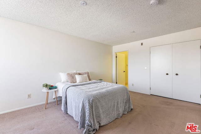 carpeted bedroom featuring a textured ceiling and a closet