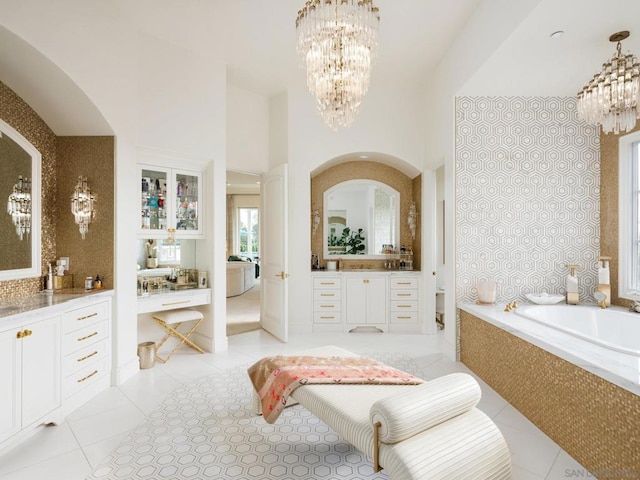 bathroom with vanity, a high ceiling, an inviting chandelier, tile patterned flooring, and tiled bath