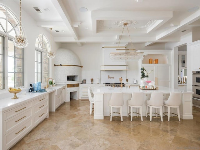 kitchen with white cabinets, hanging light fixtures, decorative backsplash, a kitchen bar, and a chandelier