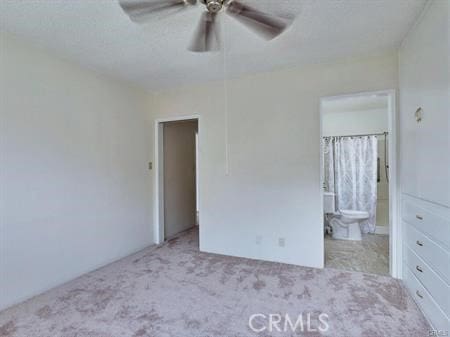 unfurnished bedroom featuring ensuite bath, ceiling fan, and light carpet