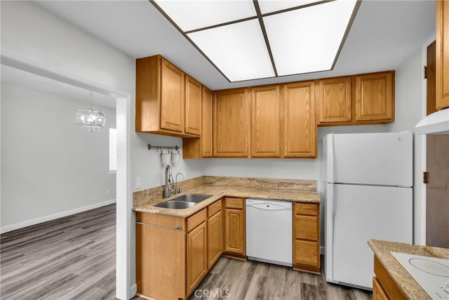 kitchen featuring sink, an inviting chandelier, wood-type flooring, decorative light fixtures, and white appliances