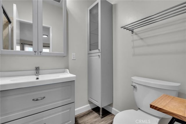 bathroom with hardwood / wood-style floors, vanity, and toilet