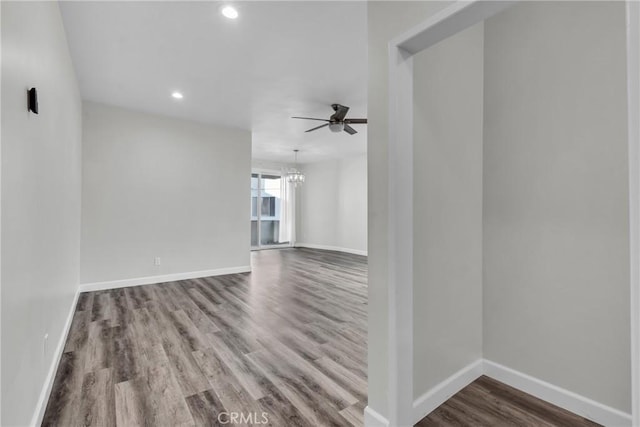 unfurnished living room featuring ceiling fan with notable chandelier and hardwood / wood-style flooring