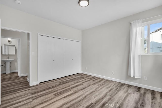 unfurnished bedroom featuring connected bathroom, a closet, and light hardwood / wood-style floors