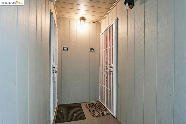 doorway featuring wooden ceiling and wooden walls