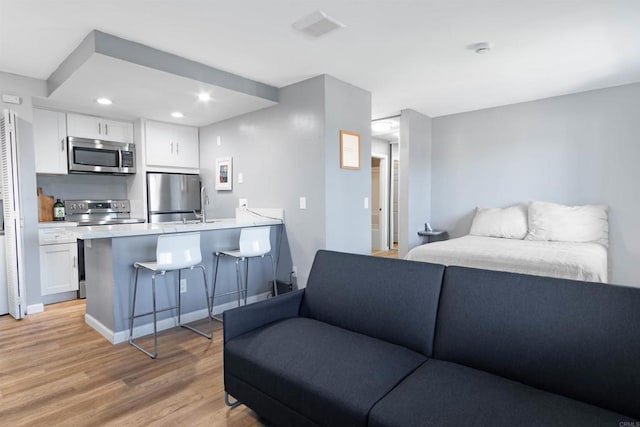 bedroom with stainless steel fridge and light hardwood / wood-style floors