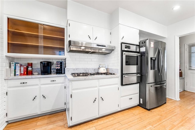 kitchen with decorative backsplash, white cabinets, light hardwood / wood-style floors, and appliances with stainless steel finishes