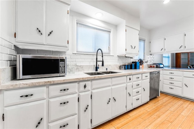 kitchen featuring white cabinetry, sink, decorative backsplash, appliances with stainless steel finishes, and light wood-type flooring