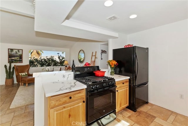 kitchen featuring light brown cabinetry and black appliances