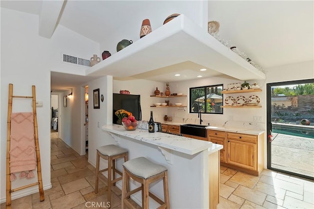 kitchen with black refrigerator, a kitchen bar, kitchen peninsula, and sink