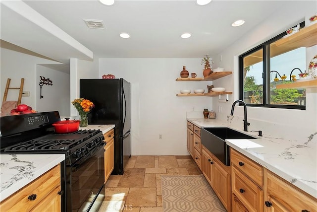 kitchen with black appliances, light stone countertops, and sink