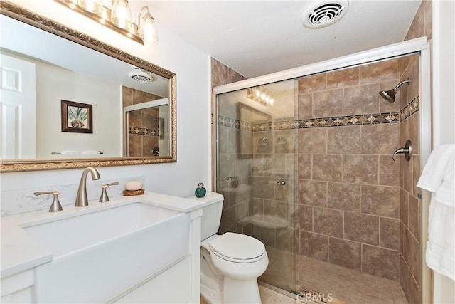 bathroom featuring vanity, a shower with shower door, and toilet