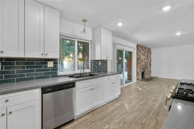 kitchen with light wood-type flooring, stainless steel appliances, sink, white cabinetry, and hanging light fixtures