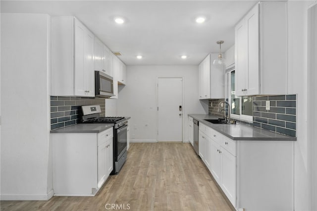 kitchen with white cabinetry, sink, stainless steel appliances, light hardwood / wood-style floors, and decorative light fixtures