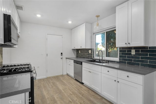 kitchen featuring hanging light fixtures, sink, light wood-type flooring, appliances with stainless steel finishes, and white cabinetry