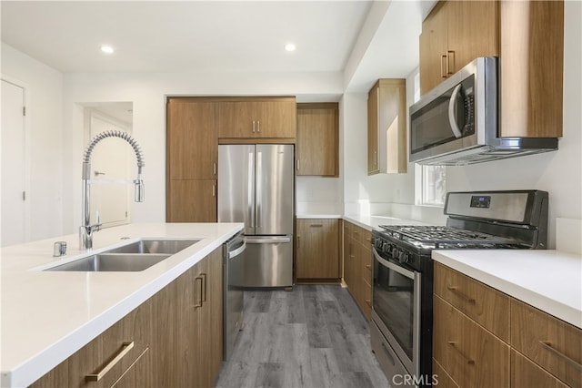 kitchen with appliances with stainless steel finishes, sink, and wood-type flooring