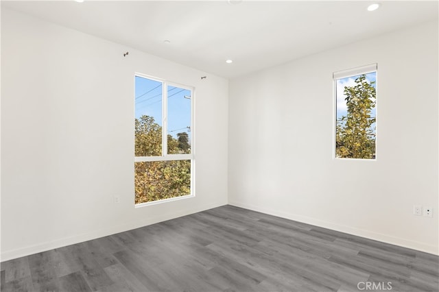 unfurnished room featuring a healthy amount of sunlight and dark hardwood / wood-style flooring