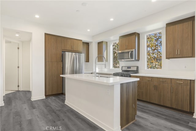 kitchen with sink, a center island with sink, dark hardwood / wood-style floors, and appliances with stainless steel finishes