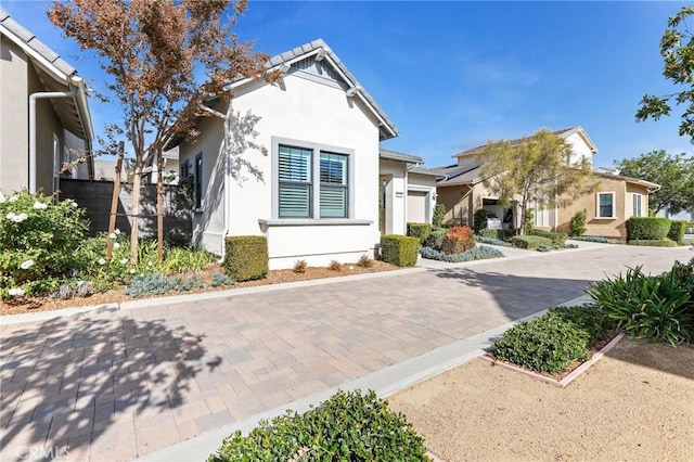 view of front of house with a garage, decorative driveway, and stucco siding