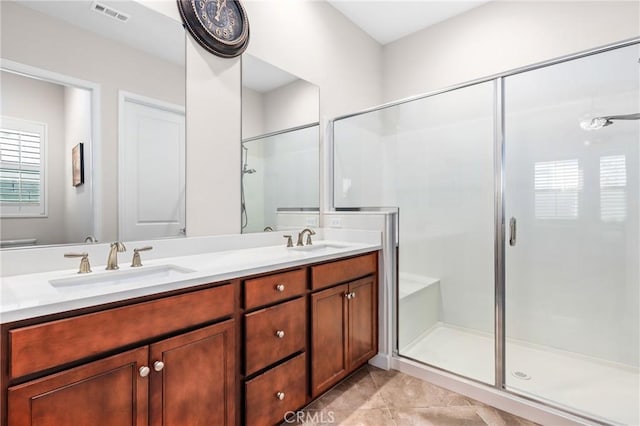 full bath featuring double vanity, a shower stall, visible vents, and a sink