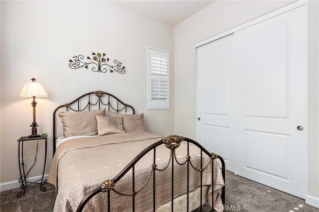 bedroom with dark colored carpet, a closet, and baseboards