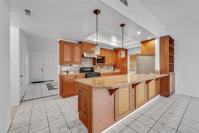 kitchen with pendant lighting, black appliances, a kitchen breakfast bar, kitchen peninsula, and a raised ceiling