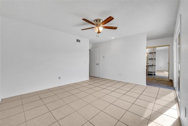 tiled empty room featuring a textured ceiling and ceiling fan