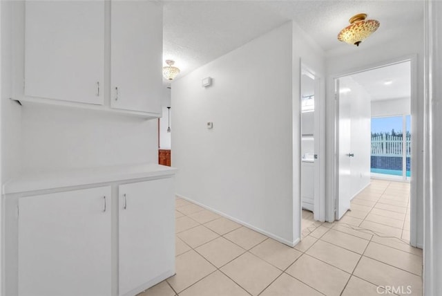 hall with a textured ceiling and light tile patterned floors