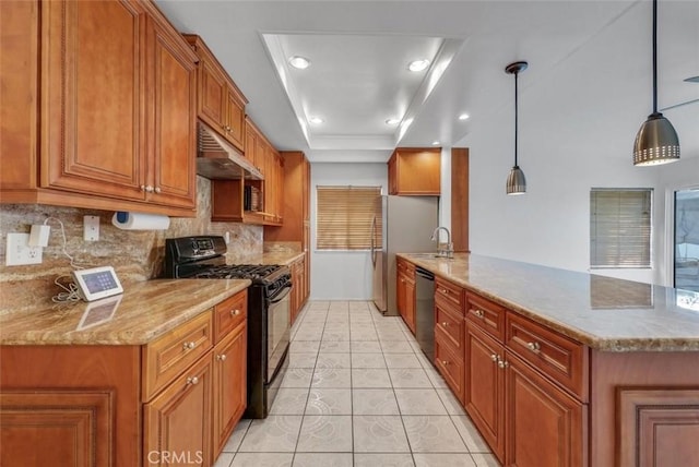 kitchen featuring pendant lighting, stainless steel appliances, decorative backsplash, a raised ceiling, and light stone counters