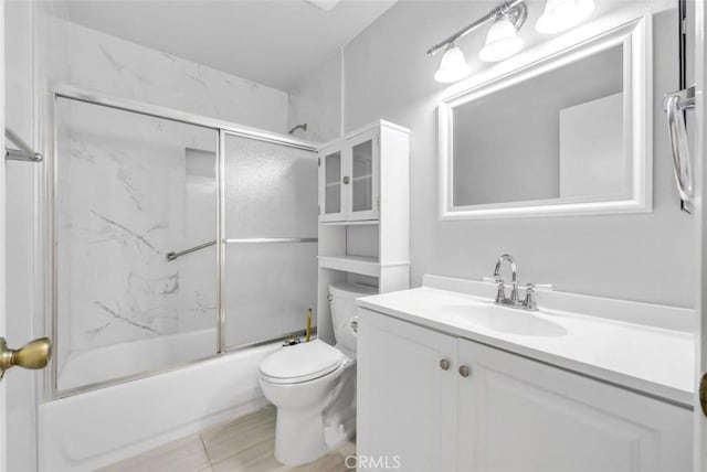 full bathroom with combined bath / shower with glass door, toilet, and vanity