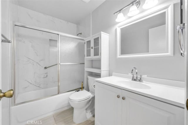 bathroom featuring vanity, combined bath / shower with glass door, and toilet