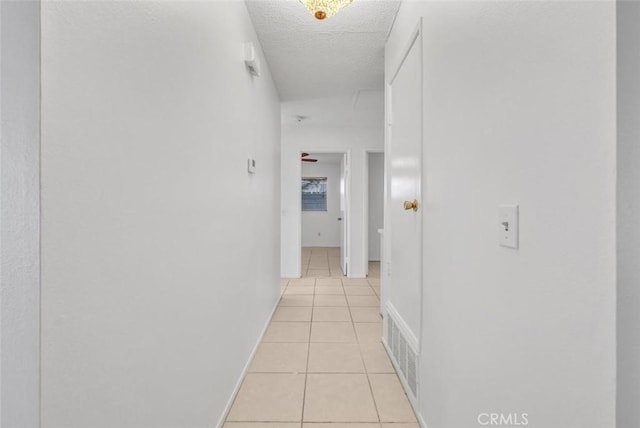 hall with a textured ceiling and light tile patterned floors